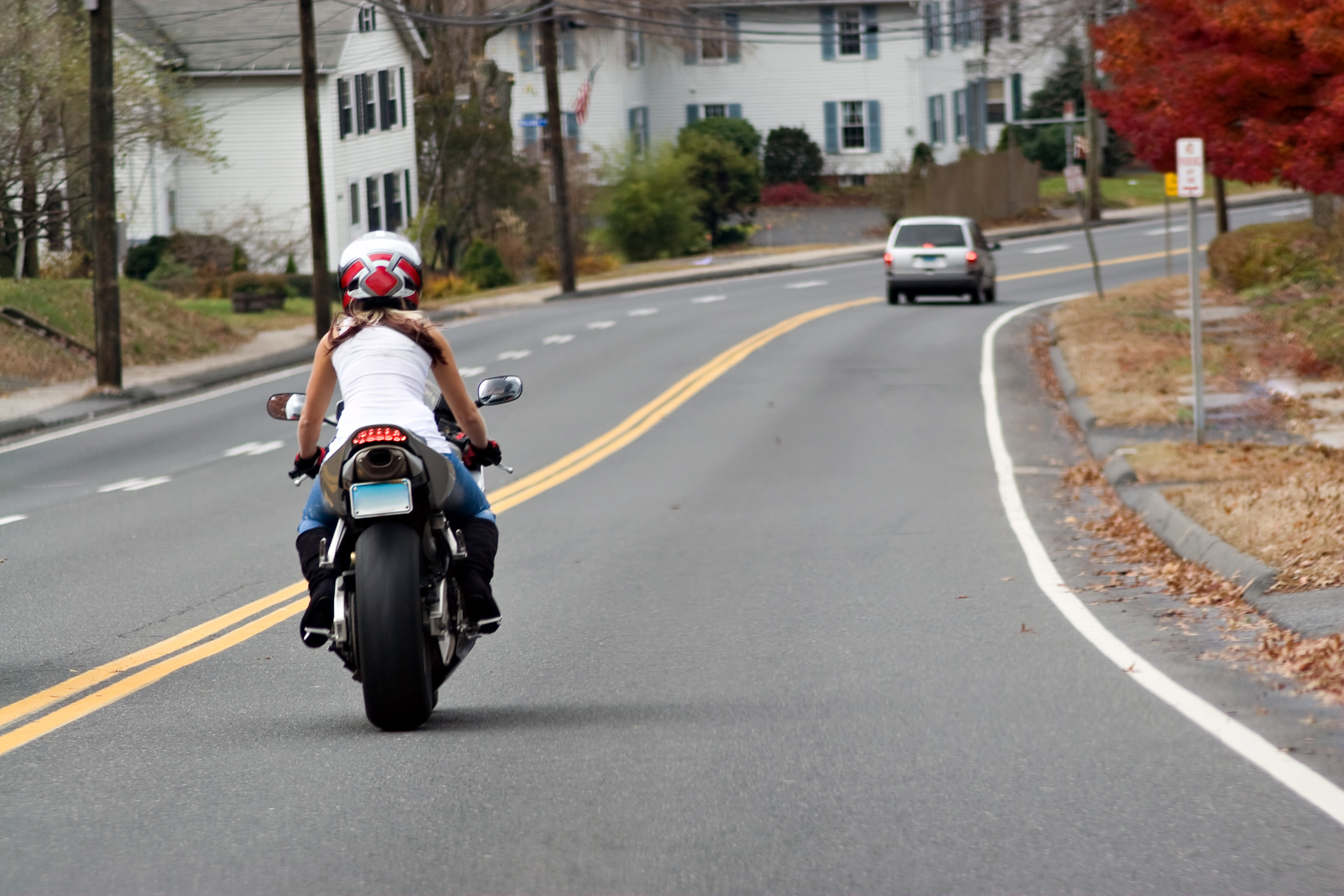 A Young Woman on a Motorcycle Maintains a Safe Following Distance with the Car Ahead