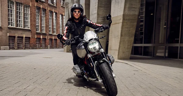 BMW R 12 nineT shown with a rider walking beside it in a city setting.